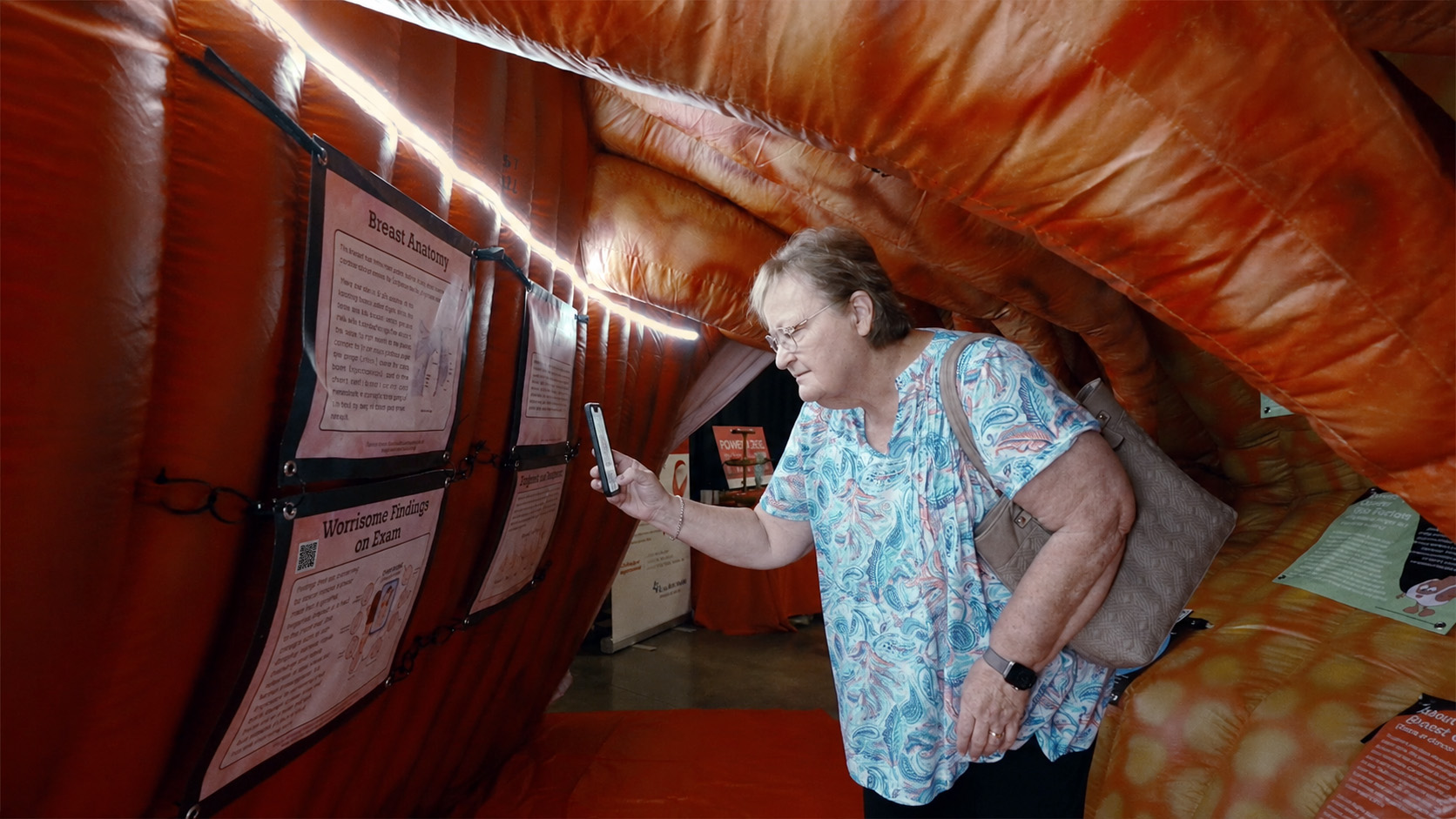 An elderly woman scanning a QR code inside an inflated exhibit